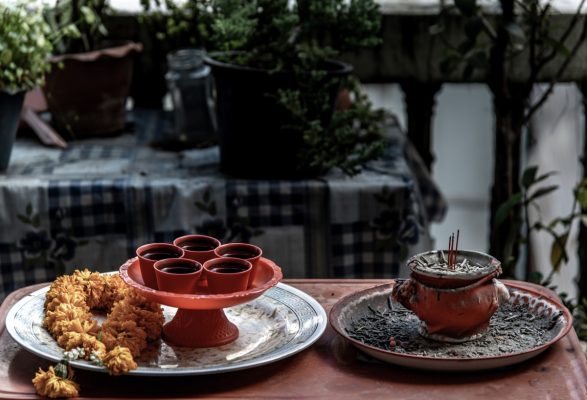 Incense burning in incense pot next to teacups and marigold flowers